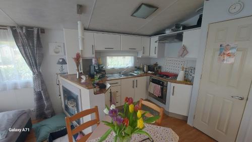 a kitchen with white cabinets and a table with flowers at Le Montourey mobihome in Fréjus