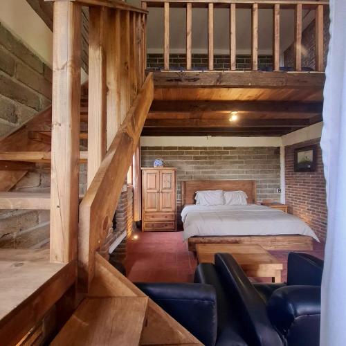 a loft bedroom with a bed and a staircase at Altépetl Cabañas Zacatlán in Tomatlán