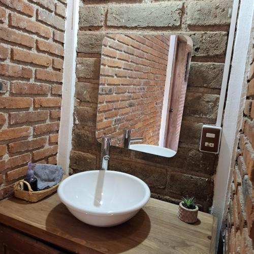 a bathroom with a white sink and a brick wall at Altépetl Cabañas Zacatlán in Tomatlán