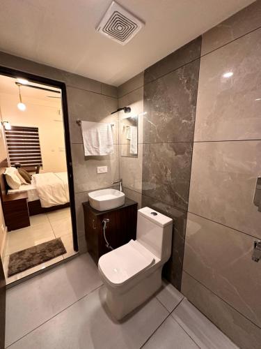 a bathroom with a toilet and a sink and a bedroom at Global Residency in Kanjirapalli