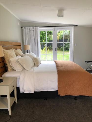 a bedroom with a large bed and a window at Waihinau Cottage - One or Two Room Options! in Otaki