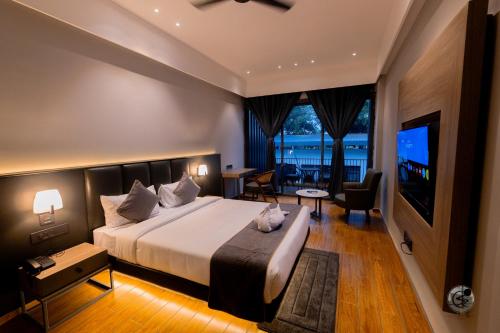 a bedroom with a large bed and a television at COUNTRYSIDE RESORT MURTi in Chālsa Mahābāri