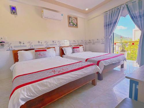 two beds in a room with a window at KHÁCH SẠN HƯNG THỊNH - Gần biển, gần cảng khách - Trung tâm Lý Sơn in Ly Son