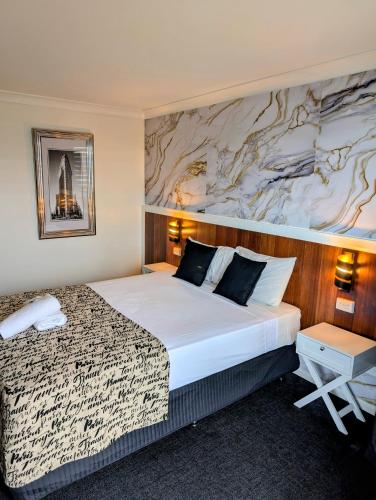 a hotel room with a large bed and a marble wall at Hampton Villa Motel in Rockhampton