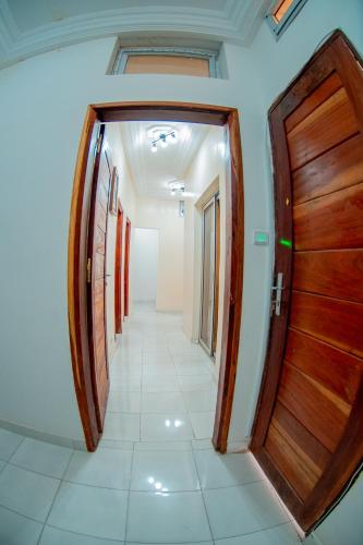un corridoio con una porta di legno e un pavimento piastrellato di Résidence Aïcha a Rufisque