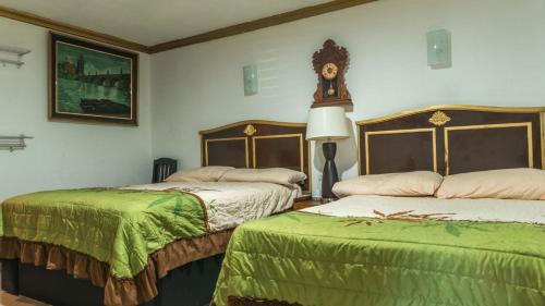 a bedroom with two beds and a clock on the wall at Hotel María Bonita by Chavira in Nuevo Laredo
