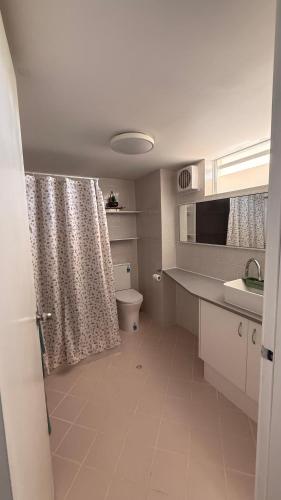 a bathroom with a toilet and a shower curtain at Mandurah Coastal Studio - Pool Outlook in Mandurah