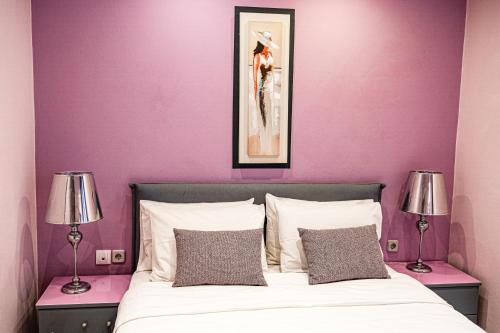 a bedroom with purple walls and a bed with two lamps at Blue Petal Apartment, Relaxed Heraklion Stay in Amoudara Herakliou