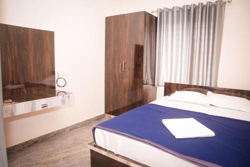 a bedroom with a bed with a blue blanket at Hotel Koyla Boarding and Lodging in Chikmagalūr