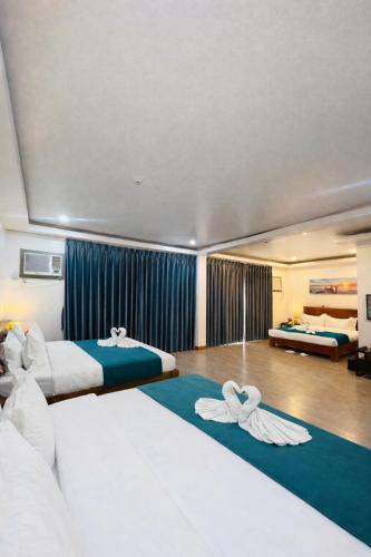 two beds in a hotel room with blue curtains at Ocean Star Hotel Coron in Coron