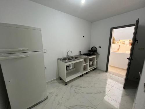 a white kitchen with a sink and a mirror at Villa Prestige sfax in Sfax