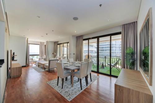 a dining room and living room with a table and chairs at Luxe Getaways Royal Amwaj Palm Jumeirah Resort Apartment Holiday Home in Dubai