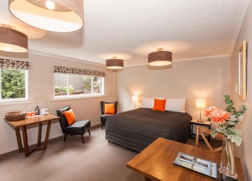 a bedroom with a bed and a desk and chairs at Wanaka View Motel in Wanaka