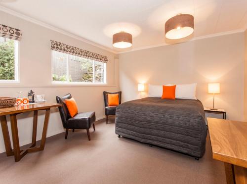 a bedroom with a bed and a desk and chairs at Wanaka View Motel in Wanaka