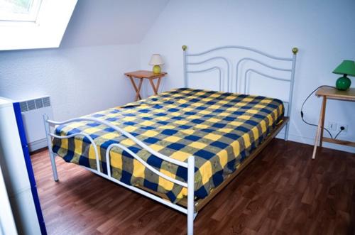 a bedroom with a bed with a blue and yellow checkered blanket at Maisonnette 6 pers- Piscine commune - Plage à 500 m- LOEIZ in Guidel-Plage