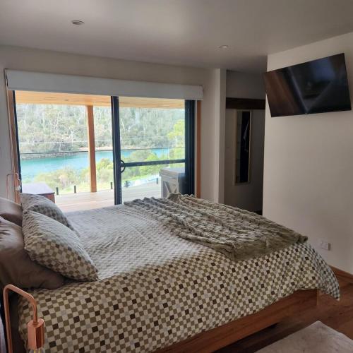 a bedroom with a bed and a large window at Prosser River view from Paradise in Orford