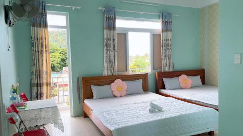 two beds in a room with a window at Hotel Kim Ngân Đảo Lý Sơn in Ly Son