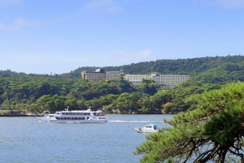 twee boten op een rivier met gebouwen op de achtergrond bij Hotel Matsushima Taikanso in Matsushima