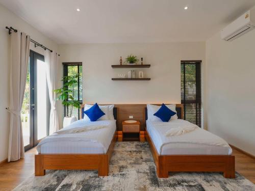 a bedroom with two beds with blue pillows at Solune Khaoyai Pool Villa in Ban Rai Khlong Sai