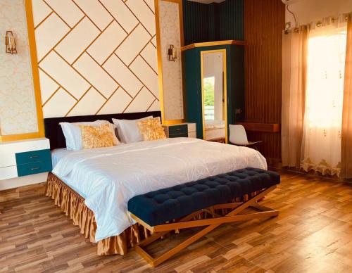 a bedroom with a large bed with a bench in it at Eastern Heritage Resort in Mymensingh