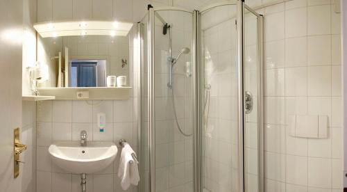 ein Bad mit einer Dusche und einem Waschbecken in der Unterkunft Hotel Villa Weststrand in Borkum