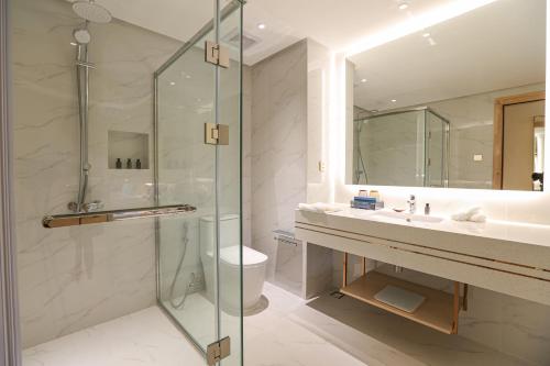 a bathroom with a glass shower and a sink at Luxu Hotel and Resort in Panglao Island