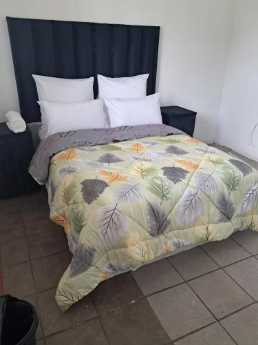 a bed with a colorful comforter on top of it at THEMBAGUESTHOUSe in Benoni