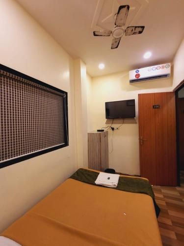 a small room with a bed and a television at Airport Inn Residency Mumbai in Mumbai