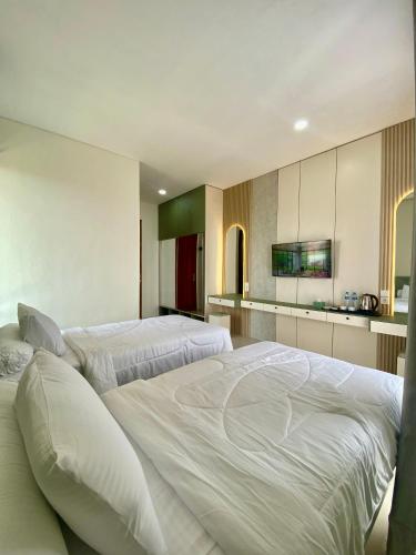 a bedroom with two beds and a kitchen at Pavo Guest House in Minangkabau International Airport