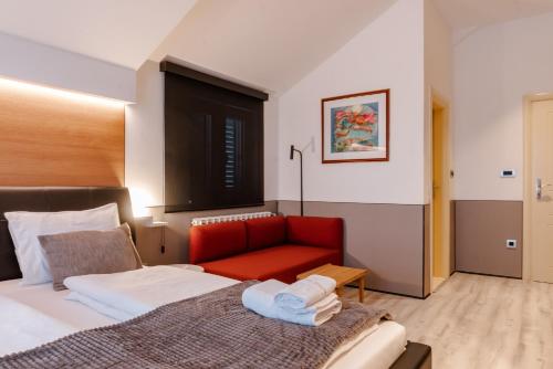 a hotel room with a bed and a red chair at Villa Dragana with heading swimming pool and parking in Budva