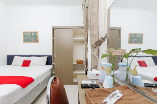 a bedroom with two beds and a desk with a table at RedDoorz at Batutulis Bogor by House of M in Bogor