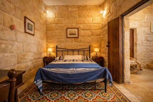 a bedroom with a bed in a stone wall at Ta' Frenc Farmhouse in Għarb