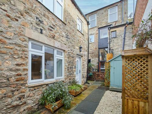 a brick building with a gate and a courtyard at Cobblers Cottage in Barnard Castle