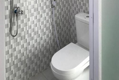 a bathroom with a white toilet and a shower at RedDoorz at Batutulis Bogor by House of M in Bogor