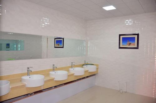 een badkamer met drie wastafels en een rij spiegels bij The Silk Road Travelers Hostel in Zhangye