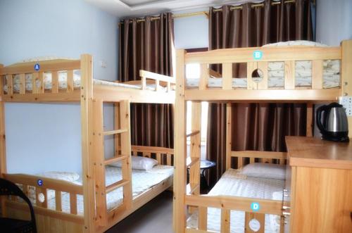 a room with three bunk beds in a room at The Silk Road Travelers Hostel in Zhangye