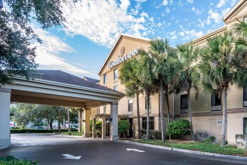 a hotel with palm trees in front of a building at Comfort Inn University in Gainesville