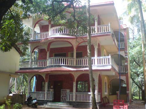 a large red brick building with a balcony at Mama Mids Home in Morjim