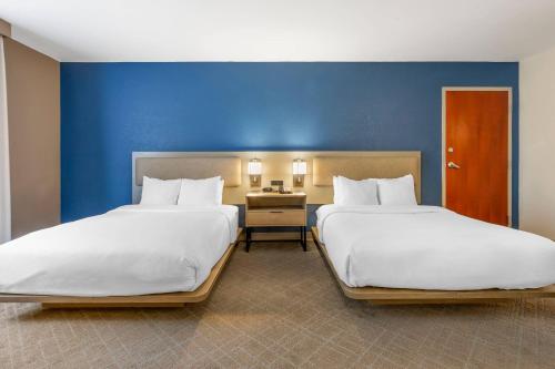 two beds in a room with a blue wall at Comfort Suites Columbia Northeast - Fort Jackson in Dentsville