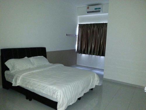 une chambre avec un lit blanc avec une fenêtre dans l'établissement Tanjung Homestay, à Ipoh
