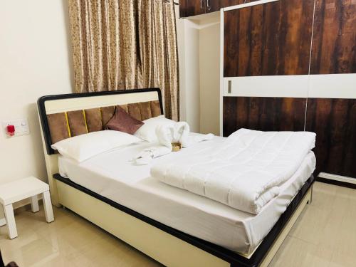 a bedroom with a large white bed with a wooden headboard at The Hampiness in Hospet