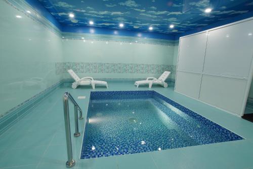 a swimming pool in a room with two chairs at Hotel Central (Vostok) in Birobidzhan