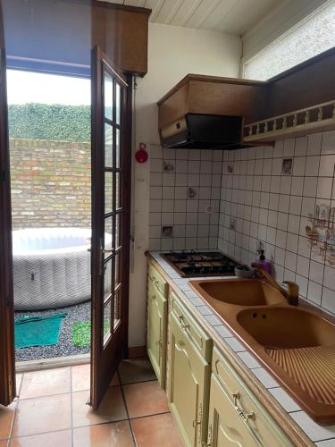 a kitchen with a sink and a stove and a window at Aux cieux enchanteurs maison magique et spa in Hondschoote