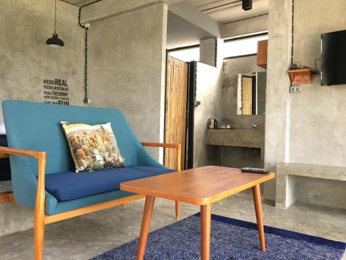 niebieskim krzesłem i drewnianym stołem w pokoju w obiekcie Twelve Oclock Resort w mieście Si Khio