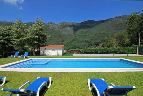 a swimming pool with three lounge chairs in the grass at Vivenda Principe in Geres