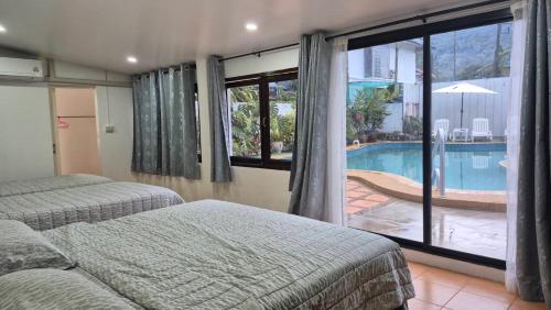 a bedroom with two beds and a swimming pool at Nur Nur Residence and villa in Surin Beach
