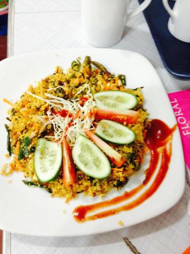 a plate of rice and vegetables with cucumbers and ketchup at SURF & SAND Hotel Arugambay in Arugam Bay