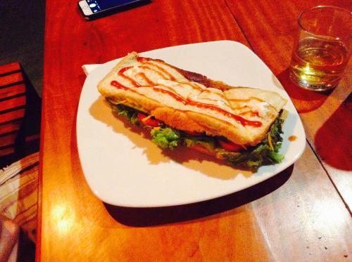 a sandwich on a white plate on a table at SURF & SAND Hotel Arugambay in Arugam Bay