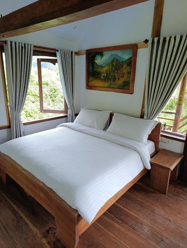a bedroom with a large bed with white sheets at SUMATRA ECORESORT in Bukittinggi