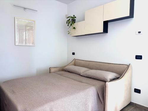 a bed in a room with a white wall at Hope Casa Vacanza Bareggio in Bareggio